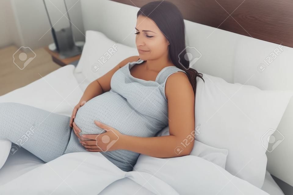 Expressão dolorosa no rosto da mulher grávida enquanto descansa na cama