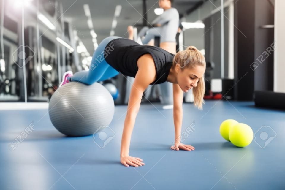 Athletic woman exercising with ball  in gym