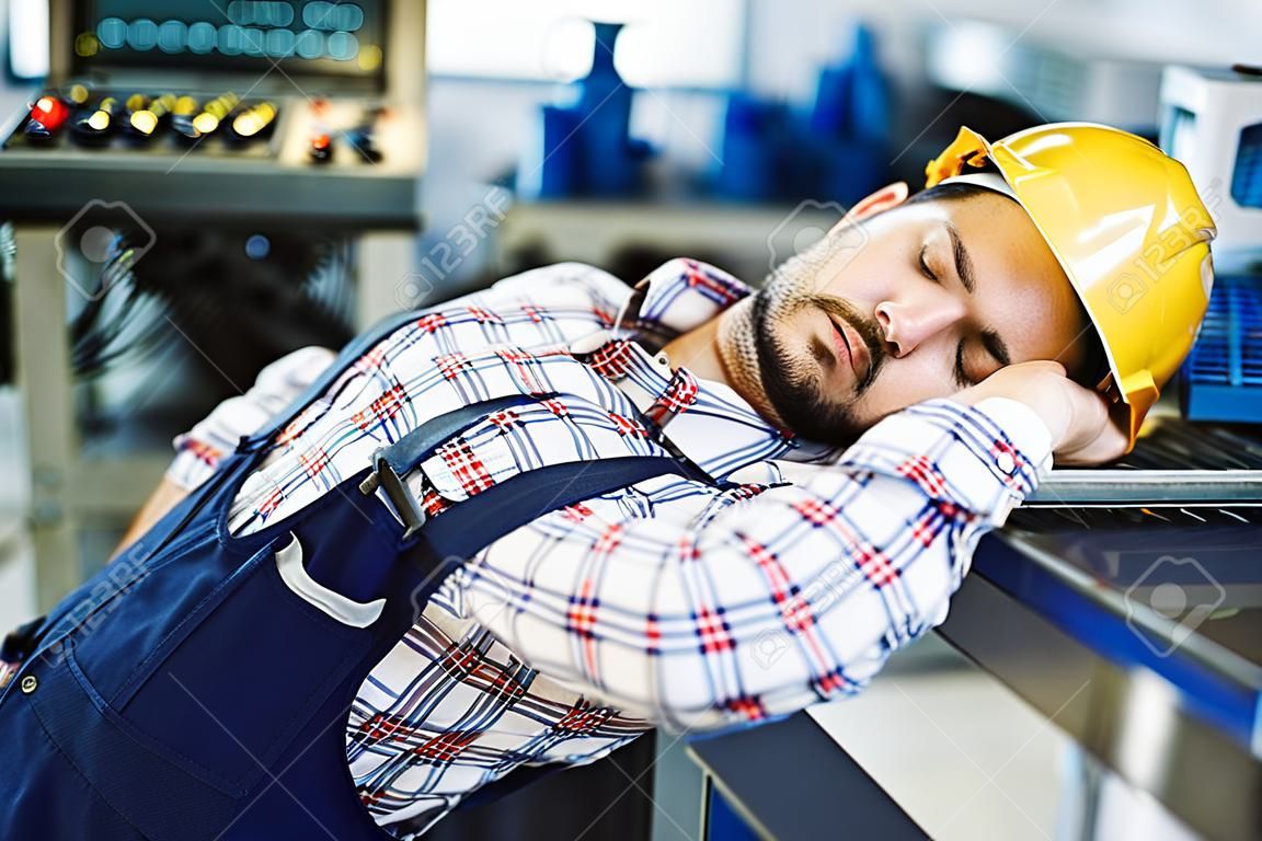 Tired overworked worker falls asleep during working hours in factory