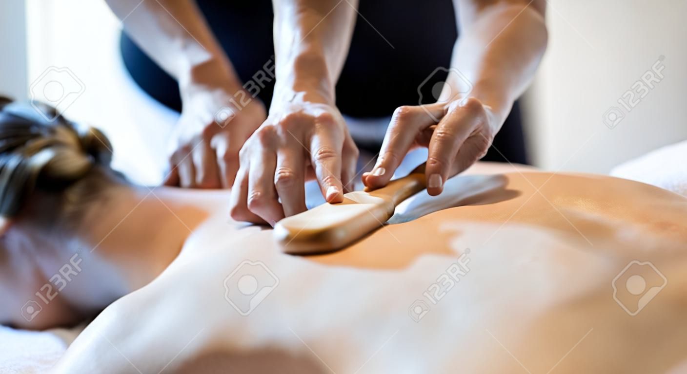 Massage therapeut met behulp van houten gereedschap te massage patiënt