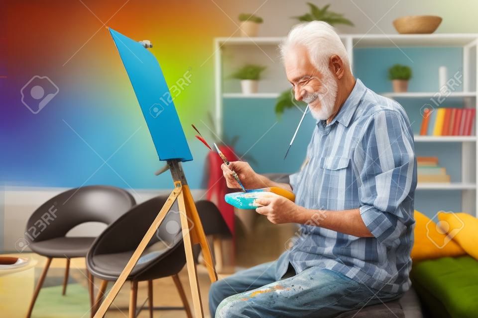Gelukkige gepensioneerde man schilderen op doek voor de lol thuis