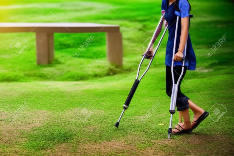 事故の観光女の子が庭で松葉杖で歩いています。タイ旅行