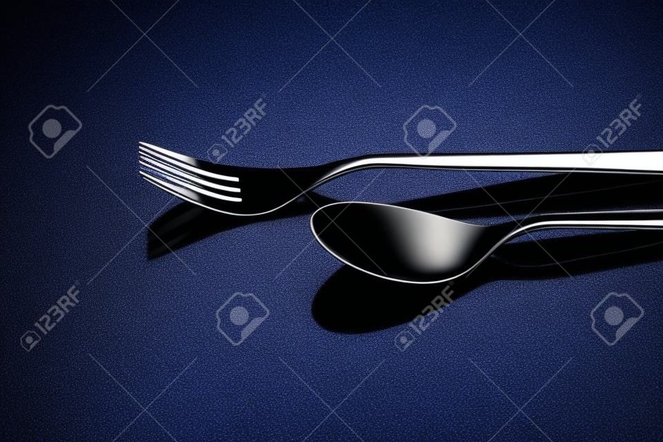 Conjunto de talheres de aço inoxidável em um fundo reflexivo preto, conceito de restaurante