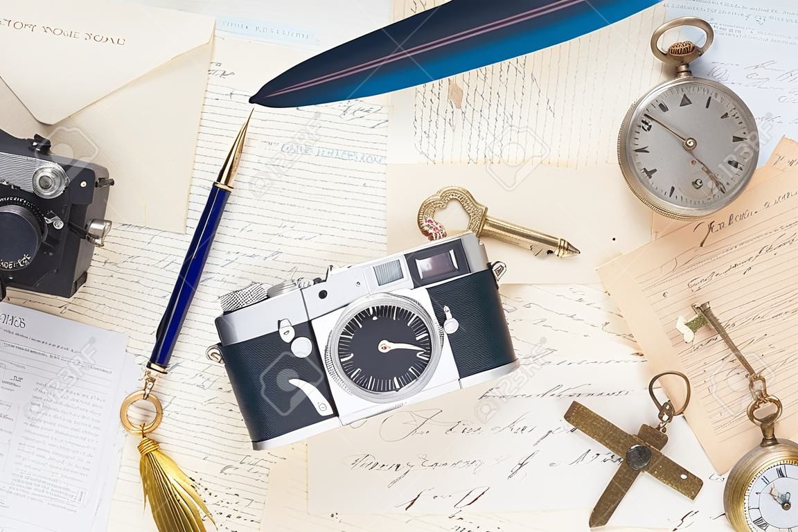 old mails background with vintage watch, feather pen, camera and key