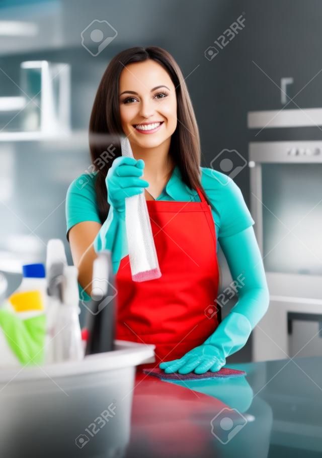 Hermosa mujer alegre morena con guantes de limpieza de la cocina moderna