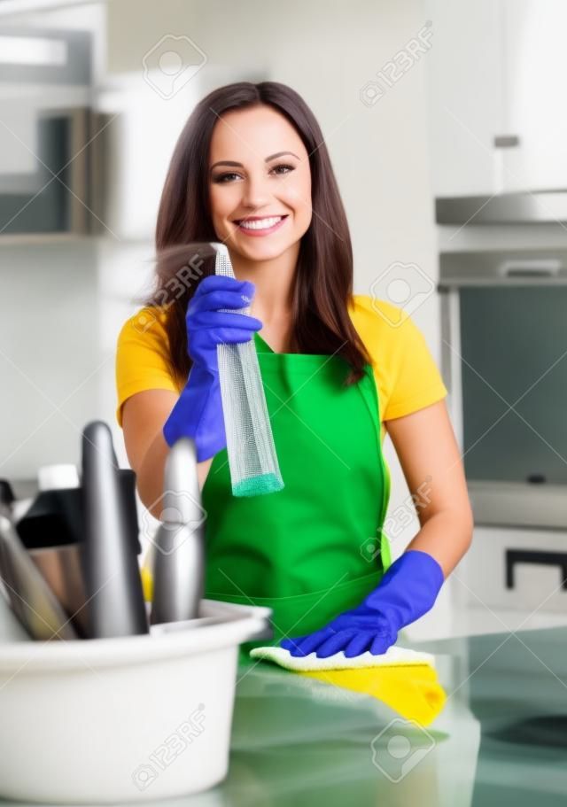 Hermosa mujer alegre morena con guantes de limpieza de la cocina moderna