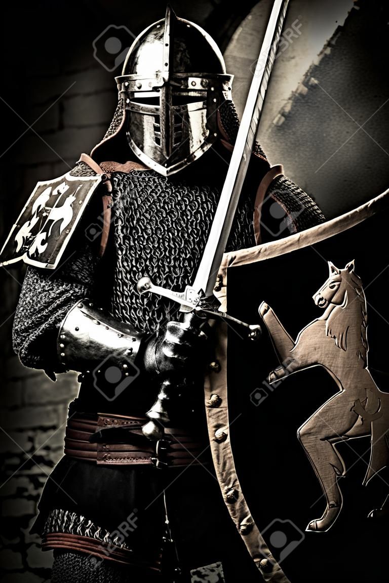 Cavaliere medievale con una spada contro il muro di pietra