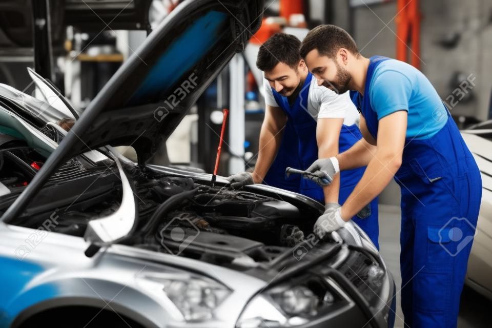 Two mechanics fixing car in a workshop
