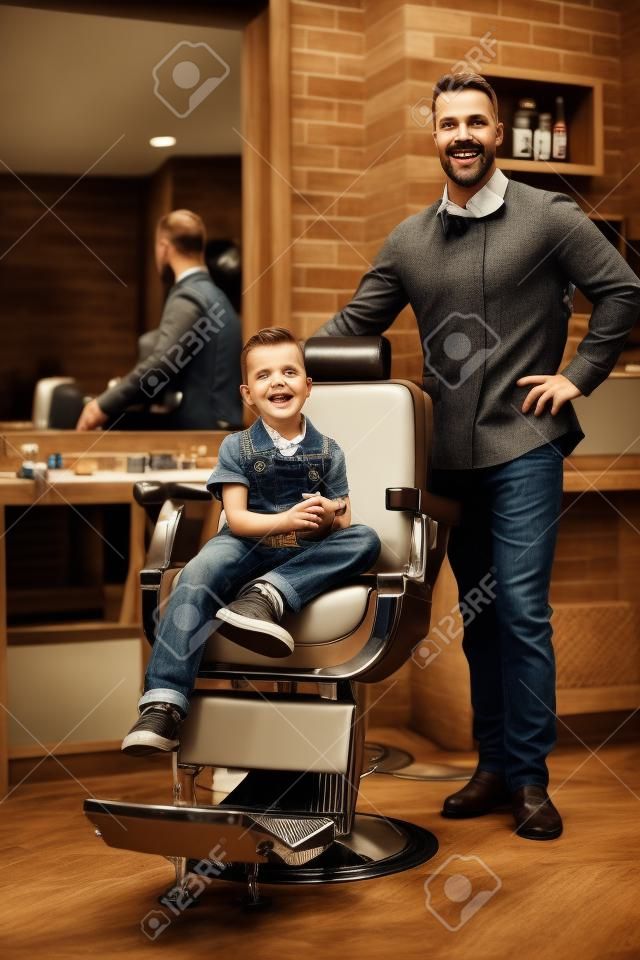 Stylish little boy and his father in a barber shop