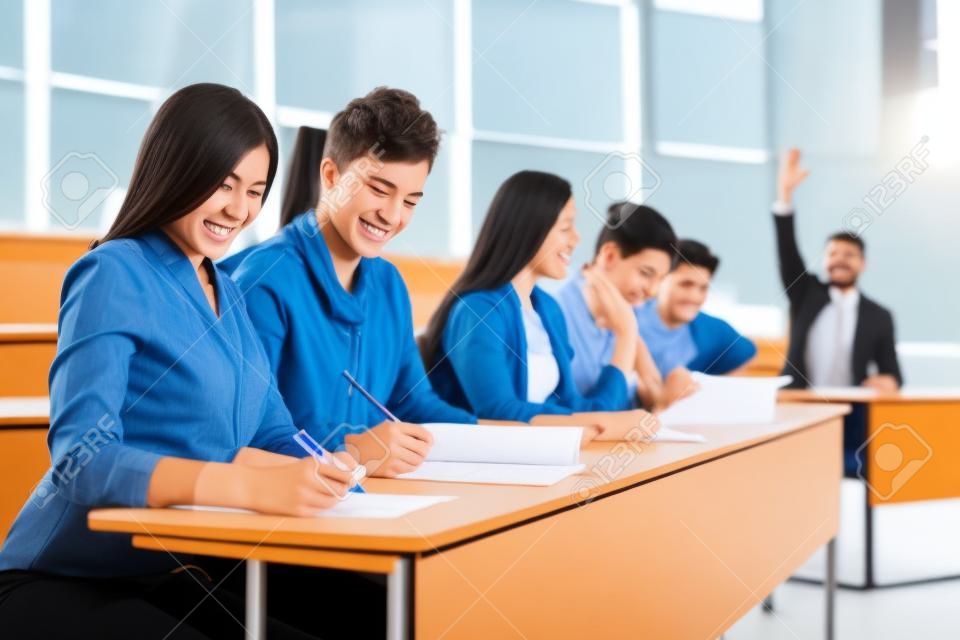 Multinational group of cheerful students taking an active part in a lesson while sitting in a lecture hall.