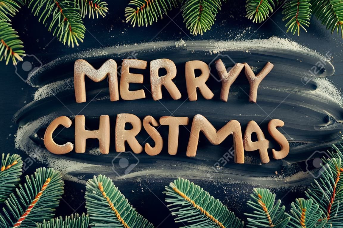 Buon Natale di Phraze dai biscotti casalinghi del pan di zenzero sul fondo scuro della lavagna. Concetto di Natale Cartolina d'auguri di stile lunatico di Natale. Felice anno nuovo. Vista dall'alto.