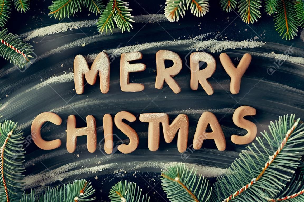 Phraze Merry Christmas from homemade gingerbread cookies on dark chalkboard background. Christmas concept. Christmas moody style greetings card. Happy New Year. Top view.