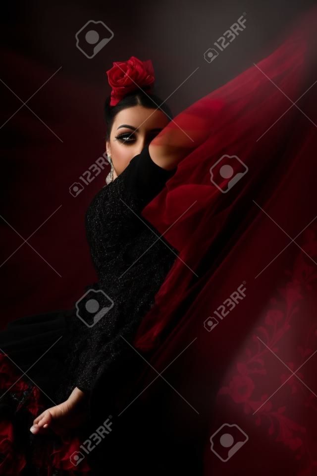 Portrait of young flamenco dancer in beautiful dress on black background.