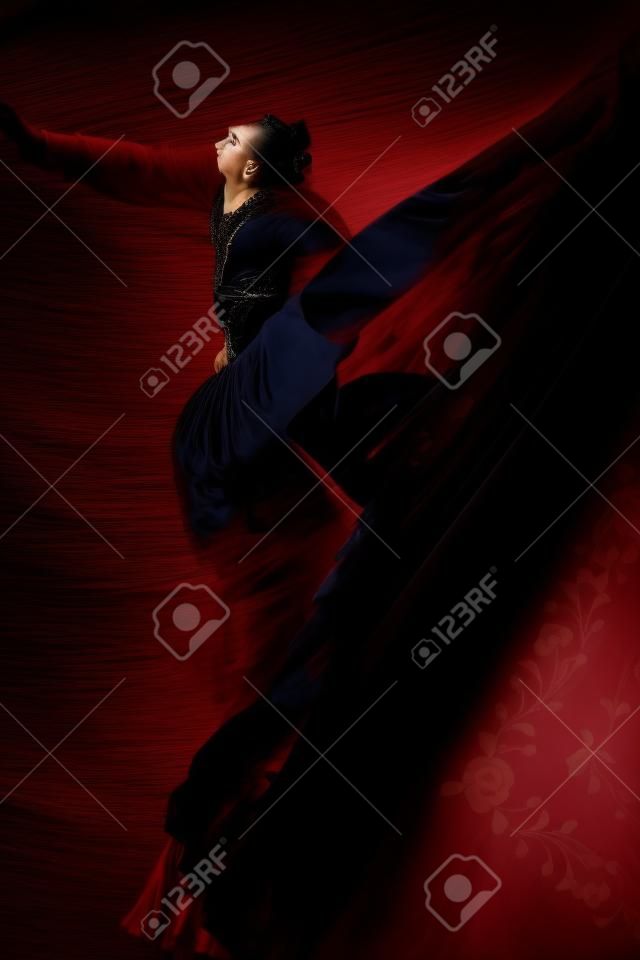 Portrait of young flamenco dancer in beautiful dress on black background.