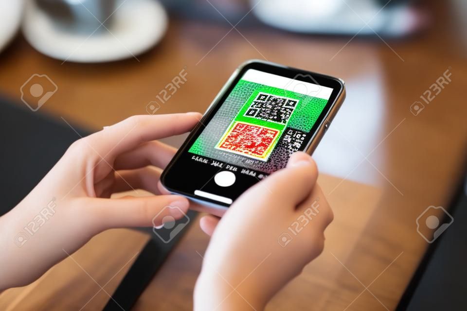 Sluiten van jonge vrouwen handen met behulp van de smartphone om te scannen van de code van het voedsel te selecteren menu in het restaurant.