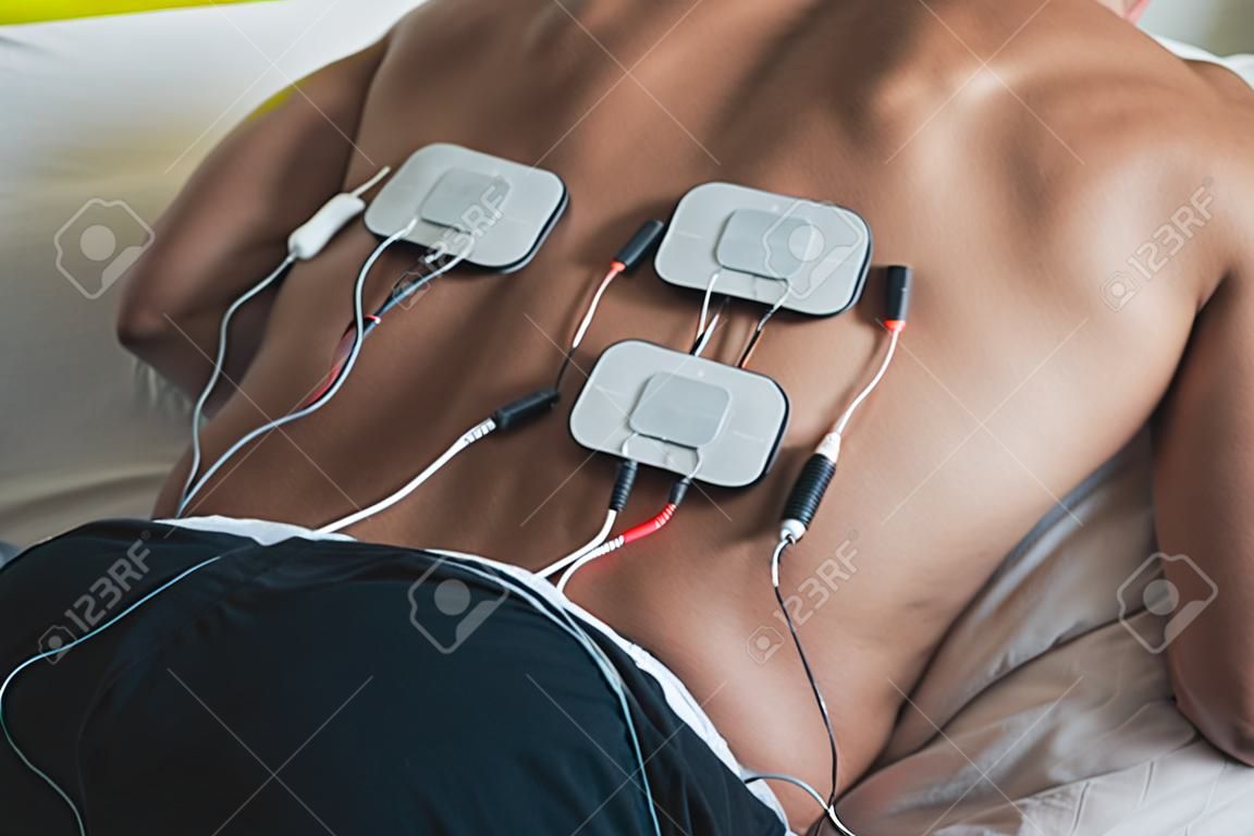 Patient applying electrical stimulation therapy on back. Electrical tens.