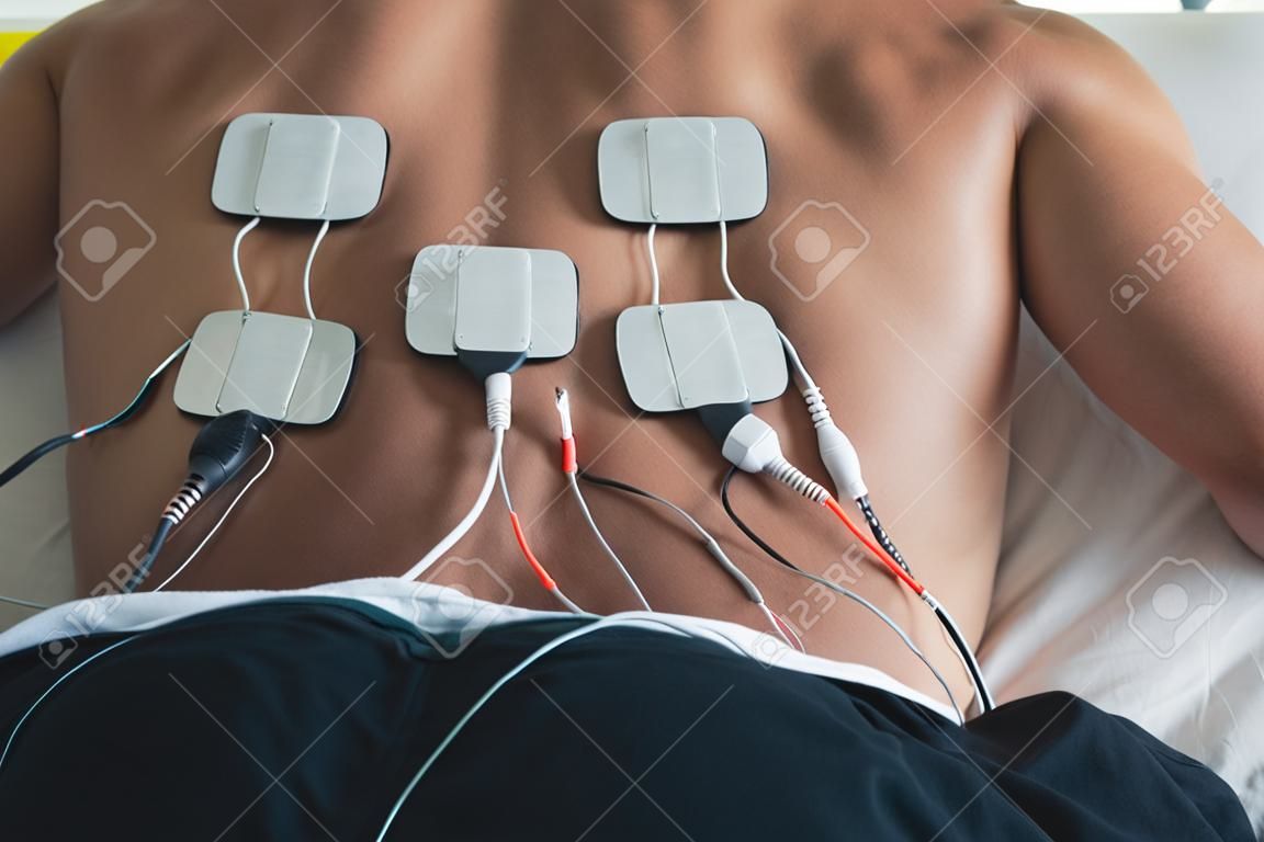 Paciente que aplica a terapia de estimulação elétrica nas costas.