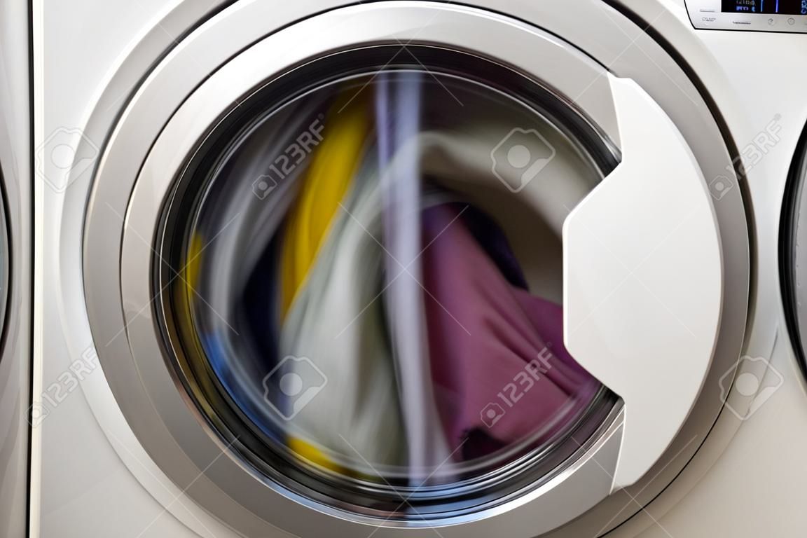 Porta da máquina de lavar roupa com roupas rotativas no interior