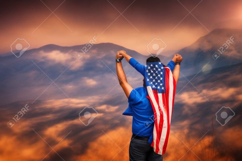 Man with child on his neck, boy on his back has an American flag on the background of nature.