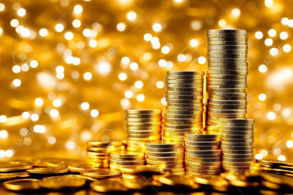 Sparkling new golden coins stacks on bright light glowing bokeh background, business finance wealth and success concept