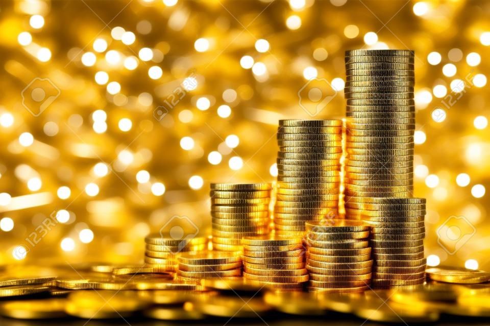 Sparkling new golden coins stacks on bright light glowing bokeh background, business finance wealth and success concept