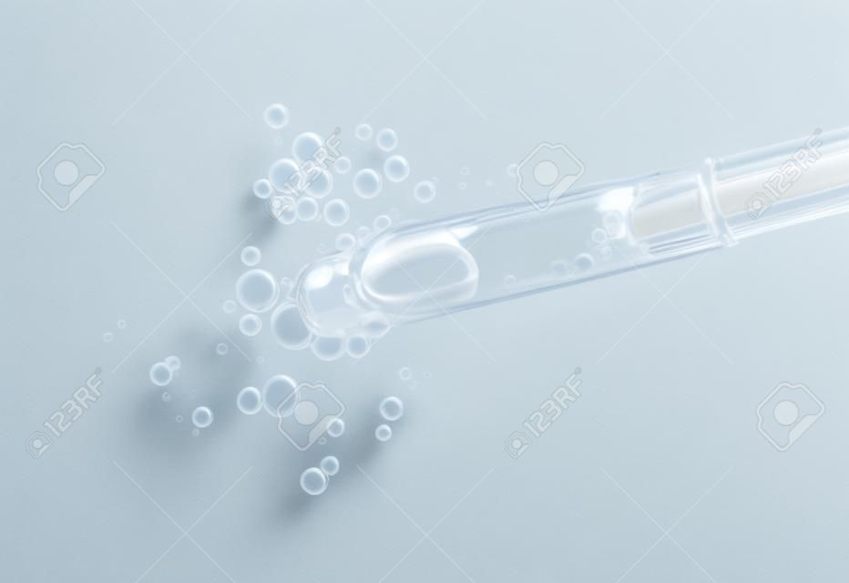 Sérum en pipette isolé sur fond blanc. Compte-gouttes liquide cosmétique avec vue de dessus de bulles.