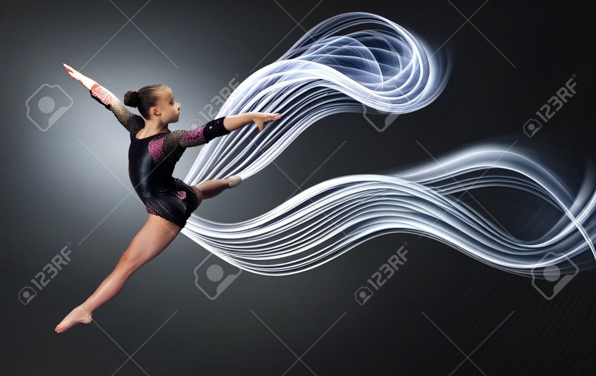 Mujer joven linda en traje de gimnasta mostrar habilidad atlética sobre fondo negro