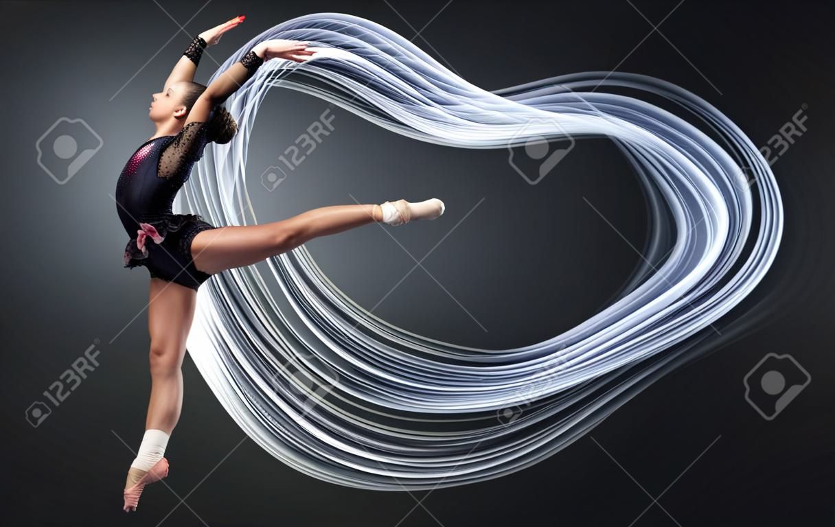 Giovane donna carino in abito ginnasta mostra abilità atletiche su sfondo nero