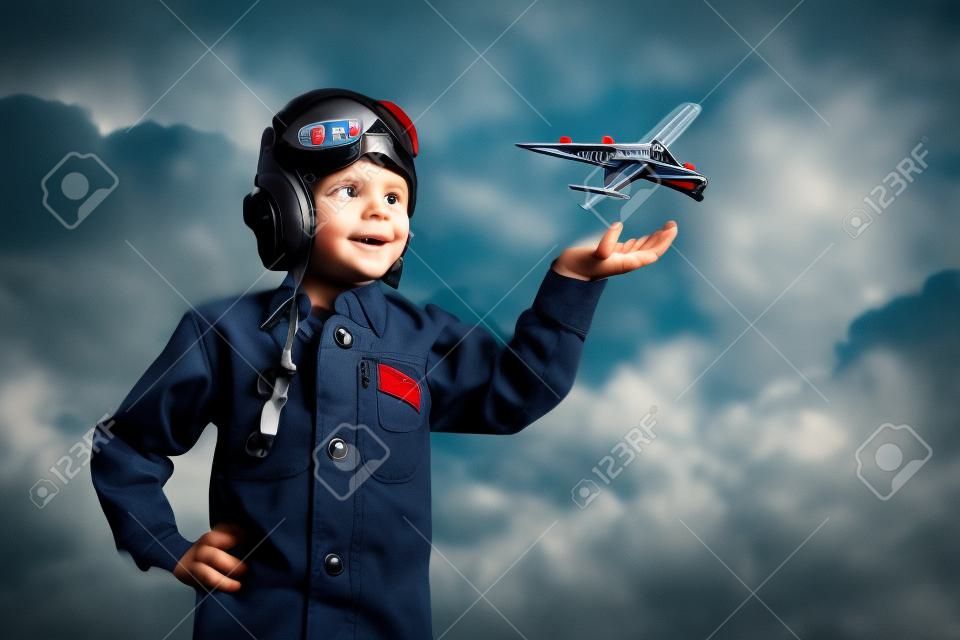 Imagen del niño pequeño en los pilotos casco con avión de juguete en la mano