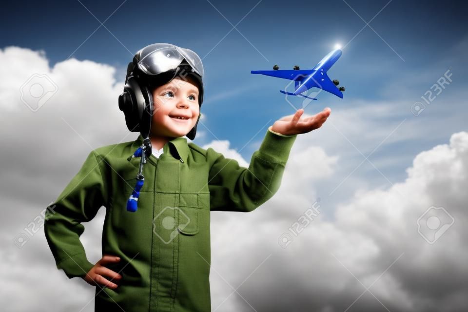 Imagen del niño pequeño en los pilotos casco con avión de juguete en la mano