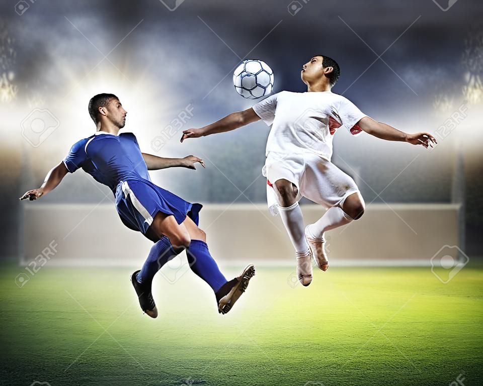 due giocatori di calcio in salto per colpire la palla allo stadio
