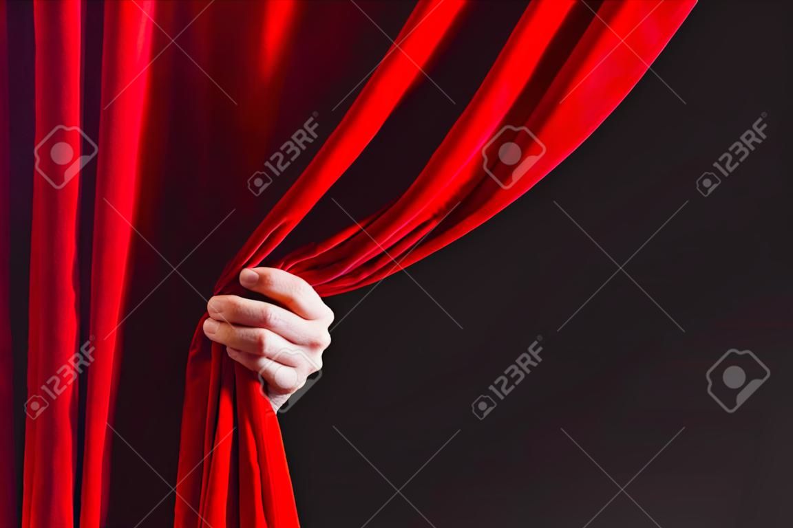 赤いカーテンの場所テキスト用開き手のクローズ アップ