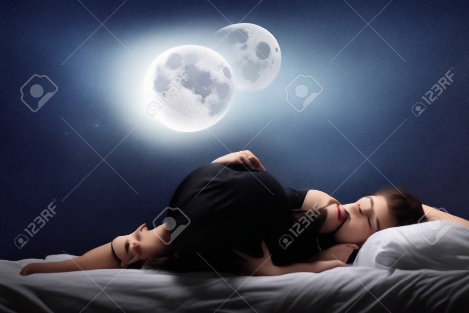Menina bonita que dorme na cama com lua