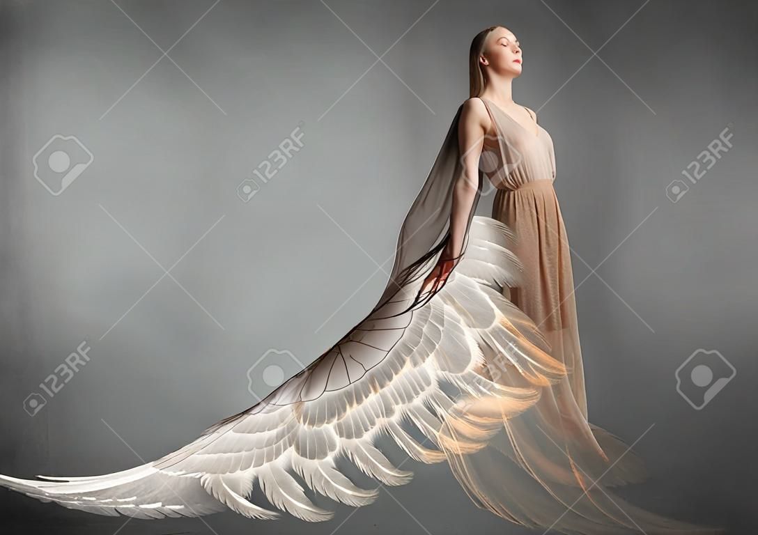 Attractive woman with angel wings on concrete background
