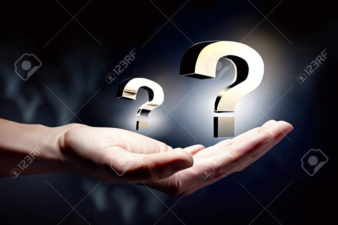 Hand holding question mark in palms on dark background