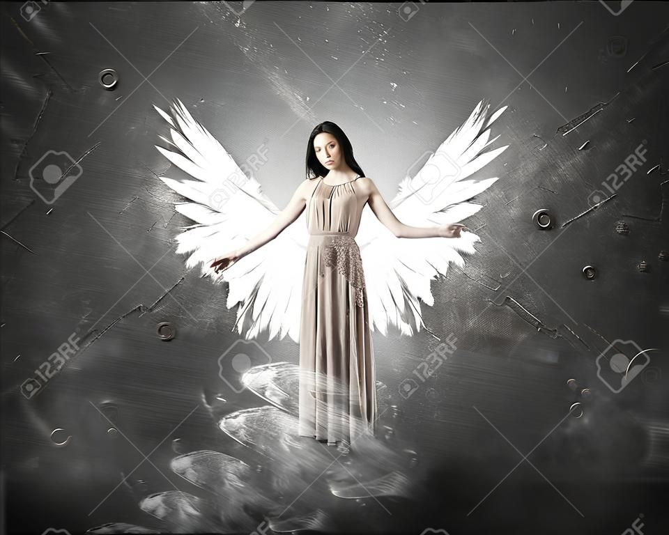 Belle femme en robe longue avec des ailes sur fond de béton