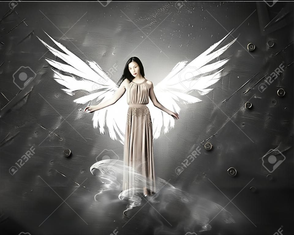 Gyönyörű nő hosszú ruhában szárnyakkal a beton háttér