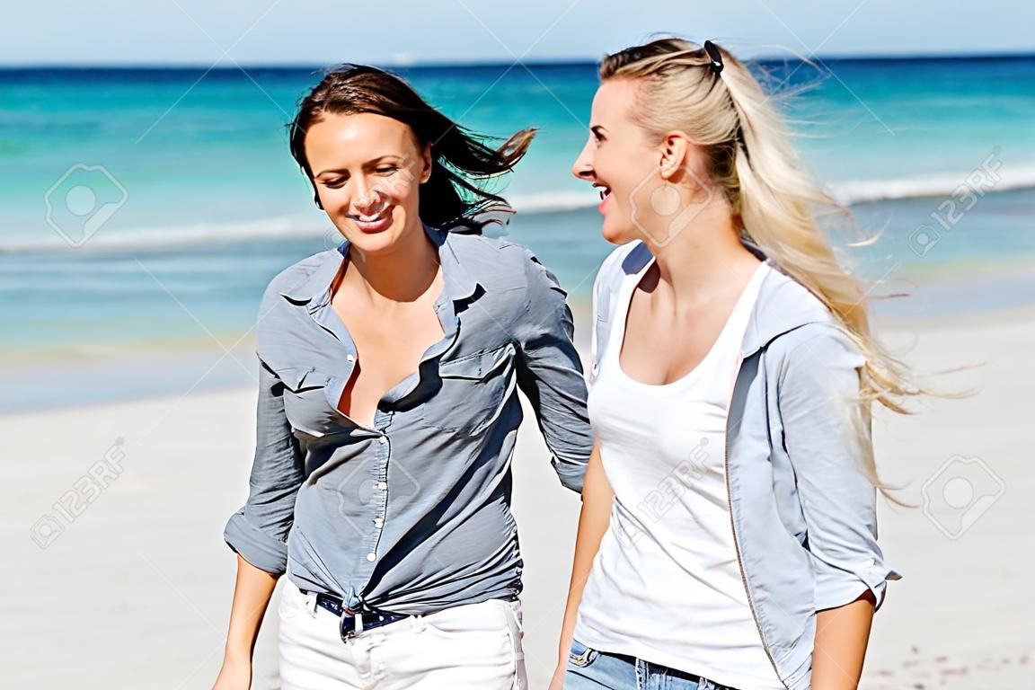 Zdjęcie przedstawiające dwie kobiety bawiące się dobrze na plaży