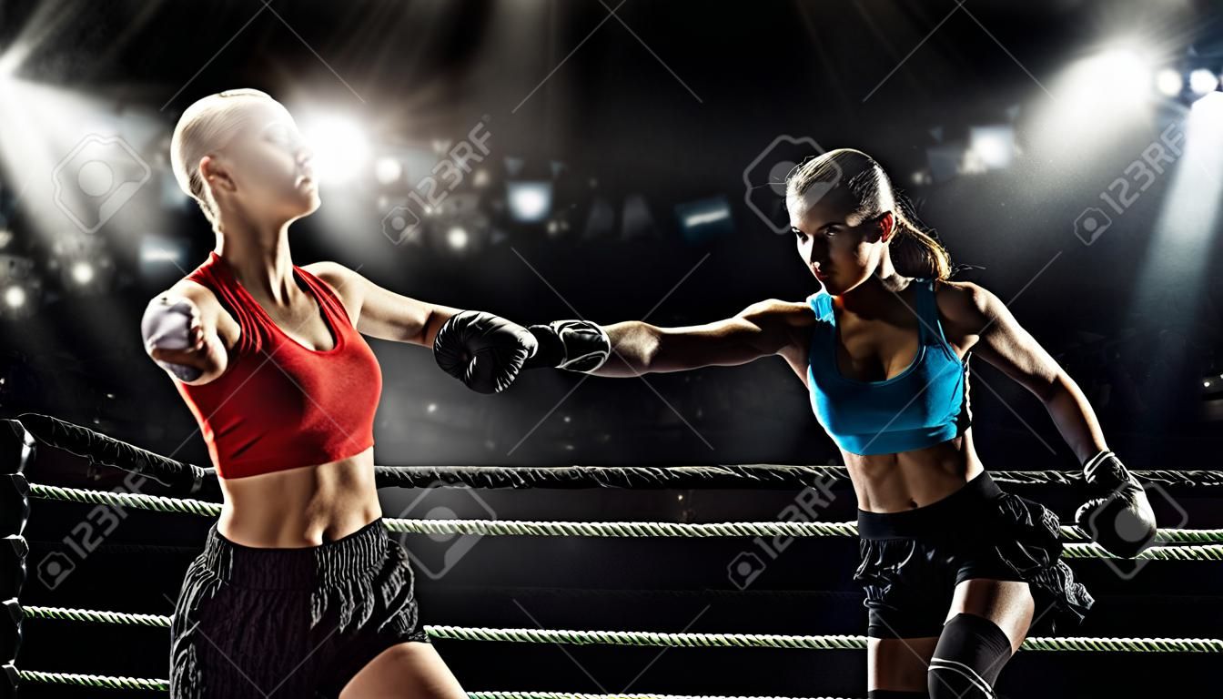 Dwie młode ładne kobiety boksują się w ringu