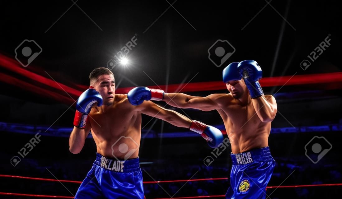 Two professional boxers fighting on arena in spotlights
