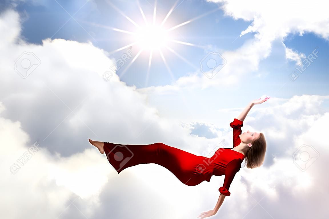 Мечтательный красивая женщина в красном платье, летающих в небе
