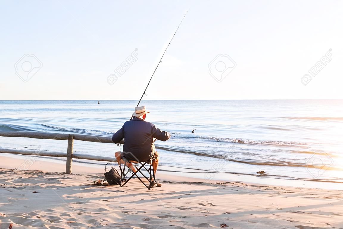 Pesca del hombre mayor en el lado del mar