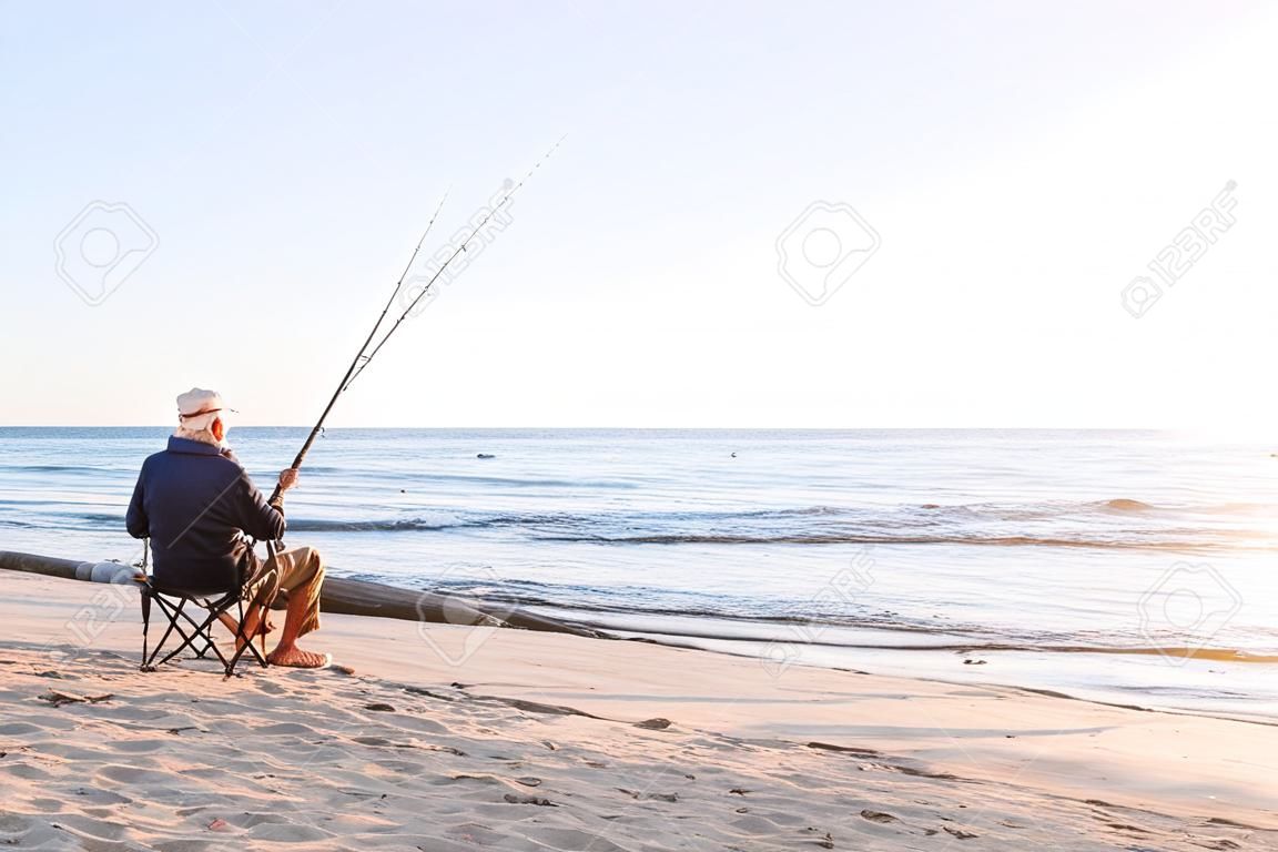 Pesca del hombre mayor en el lado del mar