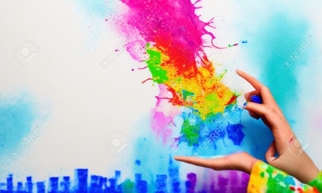 Cerca de la mano que sostiene salpicaduras de pintura colorida. Técnica mixta