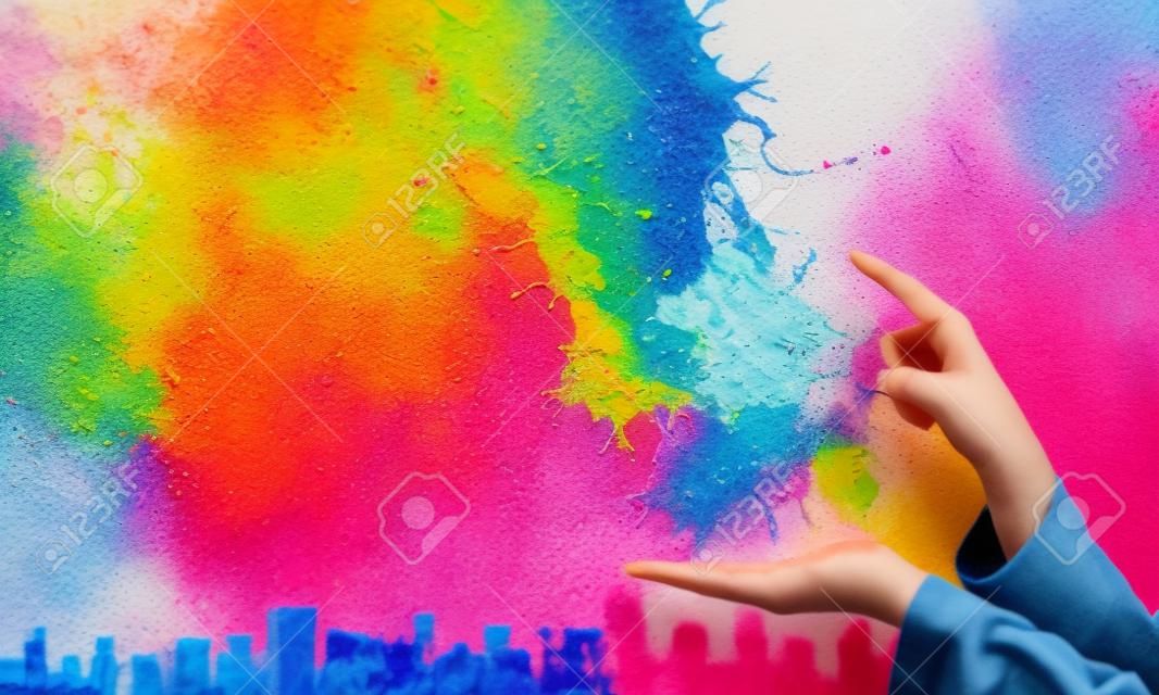 Close up of hand holding splashes of colorful paint. Mixed media