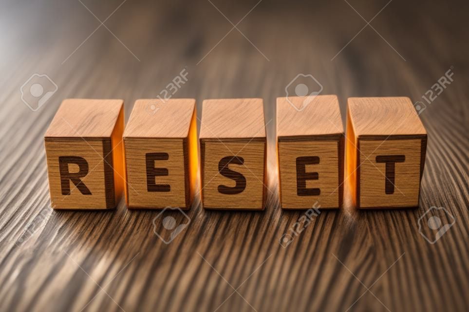 Zbliżenie słowa na drewnianym sześcianie na drewnianym biurku tła koncepcji - reset