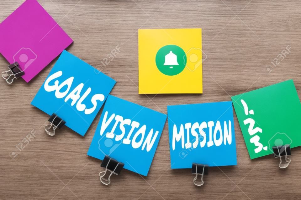 Sign displaying Goals Vision Mission. Concept meaning practical planning process used to help community group Multiple assorted collection office stationery photo placed over table