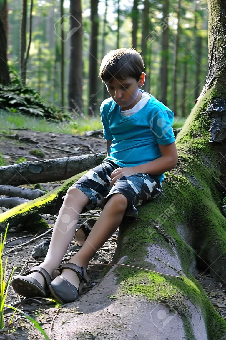 Handsome boy sitting in summer forest