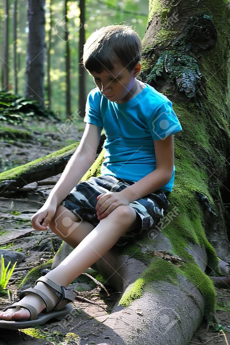 Handsome boy sitting in summer forest