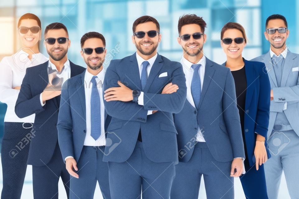 7人の成功したビジネスマンのグループは、スタイリッシュなスーツを着て男女が立って誇らしげに屋外を見ています。チームワークと多民族企業コンセプト
